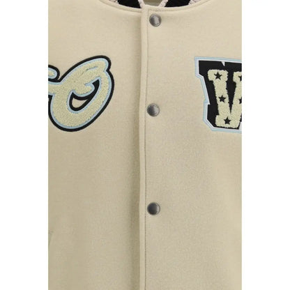 Cream-farvet varsityjakke med broderede bogstaver i sort, lyseblå og off-white på beige uldbomber